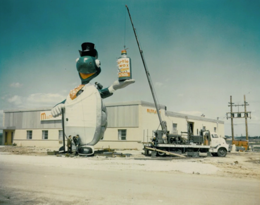 This photo was taken in front of Multiplastics — the company that constructed the sculpture for Turtle Wax — in Addison, Illinois. Different sources have this photo as allegedly taken in 1966 after it was removed, but Geoffrey Baer states it was from shortly before it's installation in 1956 (which is more likely).